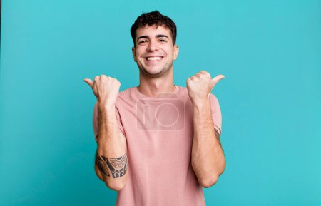 Photo for Man smiling joyfully and looking happy, feeling carefree and positive with both thumbs up - Royalty Free Image