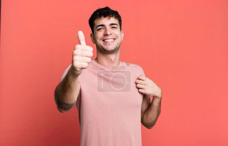 Téléchargez les photos : Homme fier, insouciant, confiant et heureux, souriant positivement avec les pouces levés - en image libre de droit