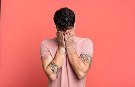 Photo for Man feeling sad, frustrated, nervous and depressed, covering face with both hands, crying - Royalty Free Image
