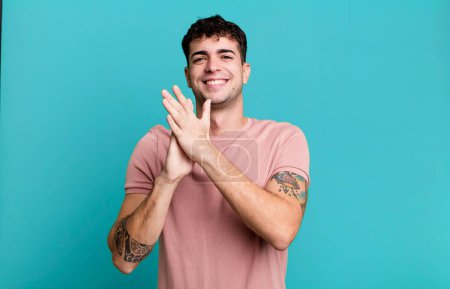 Photo for Man feeling happy and successful, smiling and clapping hands, saying congratulations with an applause - Royalty Free Image