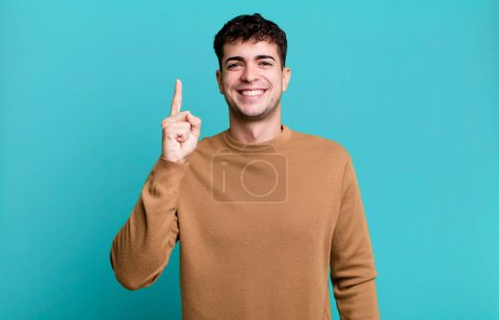 Téléchargez les photos : Homme souriant joyeusement et joyeusement, pointant vers le haut avec une main pour copier l'espace - en image libre de droit