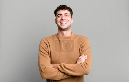 Photo for Man looking like a happy, proud and satisfied achiever smiling with arms crossed - Royalty Free Image