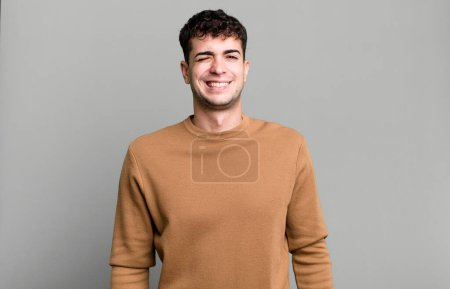 Téléchargez les photos : Homme regardant heureux et amical, souriant et clin d'oeil à vous avec une attitude positive - en image libre de droit