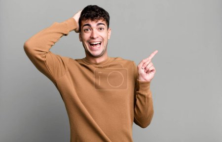 Foto de Hombre riendo, luciendo feliz, positivo y sorprendido, realizando una gran idea apuntando al espacio de copia lateral - Imagen libre de derechos