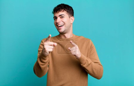 Photo for Man smiling with a positive, successful, happy attitude pointing to the camera, making gun sign with hands - Royalty Free Image
