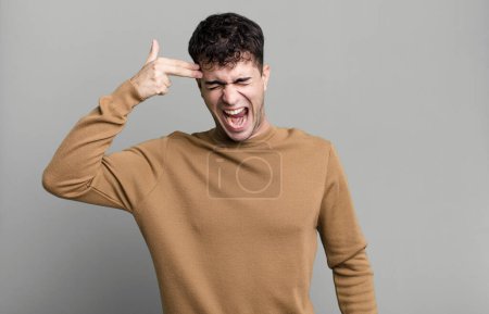 Foto de Hombre que parece infeliz y estresado, gesto suicida haciendo señal de arma con la mano, apuntando a la cabeza - Imagen libre de derechos