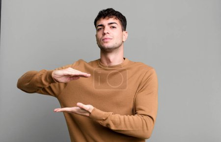 Photo for Man holding an object with both hands on side copy space, showing, offering or advertising an object - Royalty Free Image