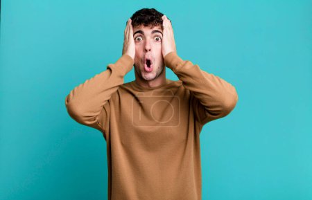 Photo for Man looking unpleasantly shocked, scared or worried, mouth wide open and covering both ears with hands - Royalty Free Image