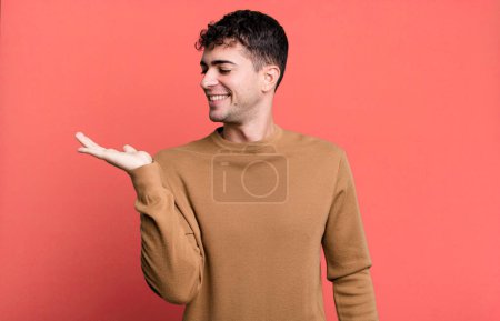 Photo for Man feeling happy and smiling casually, looking to an object or concept held on the hand on the side - Royalty Free Image
