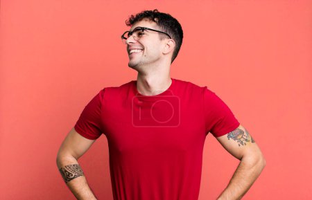 Photo for Looking happy, cheerful and confident, smiling proudly and looking to side with both hands on hips - Royalty Free Image