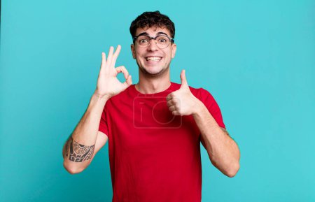 Photo for Man feeling happy, amazed, satisfied and surprised, showing okay and thumbs up gestures, smiling - Royalty Free Image