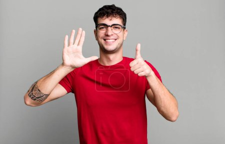 Foto de Sonriendo y mirando amigable, mostrando el número seis o sexto con la mano hacia adelante, cuenta atrás - Imagen libre de derechos