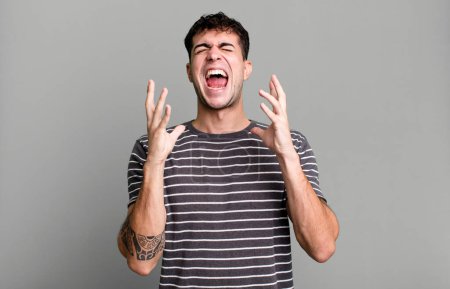 Photo for Furiously screaming, feeling stressed and annoyed with hands up in the air saying why me - Royalty Free Image