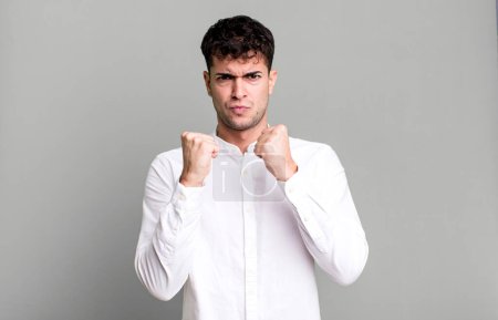 Téléchargez les photos : Homme confiant, en colère, fort et agressif, avec les poings prêts à se battre en position de boxe - en image libre de droit