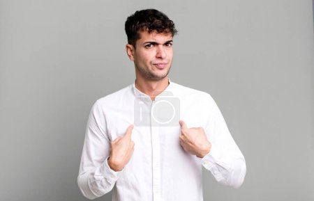 Foto de Hombre apuntando a sí mismo con una mirada confusa y cuestionable, sorprendido y sorprendido de ser elegido - Imagen libre de derechos