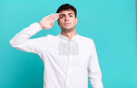 Téléchargez les photos : Homme saluant la caméra avec un salut militaire dans un acte d'honneur et de patriotisme, faisant preuve de respect - en image libre de droit