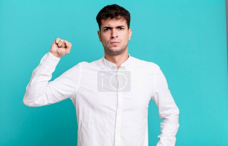 Photo for Man feeling serious, strong and rebellious, raising fist up, protesting or fighting for revolution - Royalty Free Image