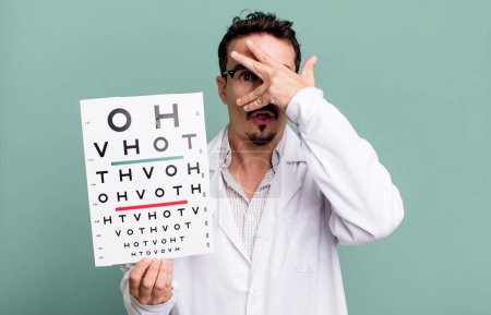 Photo for Adult man looking shocked, scared or terrified, covering face with hand. optical vision test concept - Royalty Free Image