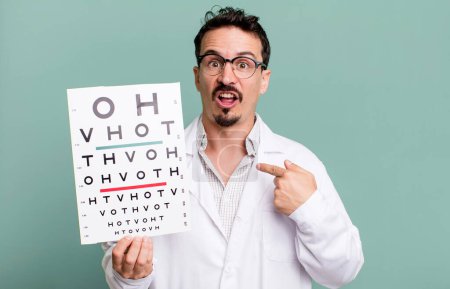 Foto de Adult man looking shocked and surprised with mouth wide open, pointing to self. optical vision test concept - Imagen libre de derechos