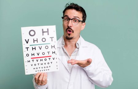 Photo for Adult man looking surprised and shocked, with jaw dropped holding an object. optical vision test concept - Royalty Free Image
