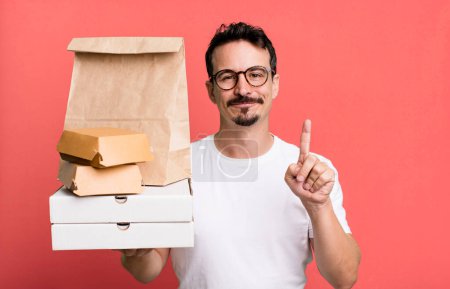 Photo for Adult man smiling and looking friendly, showing number one. fast food delivery and take away concept - Royalty Free Image
