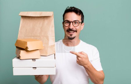 Photo for Adult man looking excited and surprised pointing to the side. fast food delivery and take away concept - Royalty Free Image