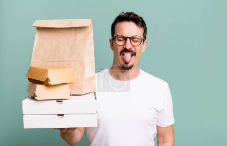 Foto de Adult man feeling disgusted and irritated and tongue out. fast food delivery and take away concept - Imagen libre de derechos