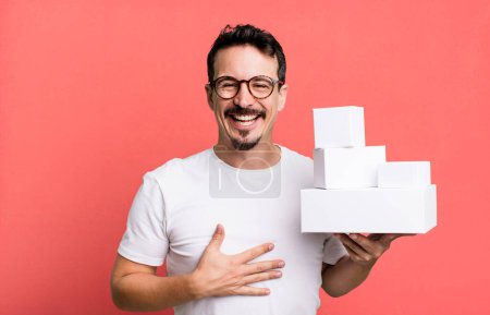 Téléchargez les photos : Adult man laughing out loud at some hilarious joke. blank boxes packaging concept - en image libre de droit