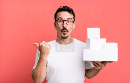 Téléchargez les photos : Adult man looking astonished in disbelief. blank boxes packaging concept - en image libre de droit