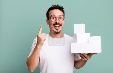 Téléchargez les photos : Adult man feeling like a happy and excited genius after realizing an idea. blank boxes packaging concept - en image libre de droit