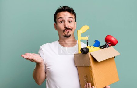 Téléchargez les photos : Adult man feeling puzzled and confused and doubting. with a toolbox. handyman concept - en image libre de droit