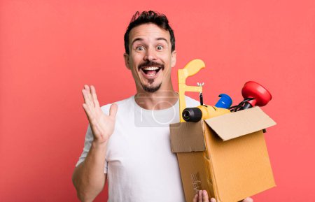 Foto de Adult man feeling happy and astonished at something unbelievable. with a toolbox. handyman concept - Imagen libre de derechos