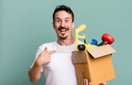 Foto de Adult man feeling happy and pointing to self with an excited. with a toolbox. handyman concept - Imagen libre de derechos