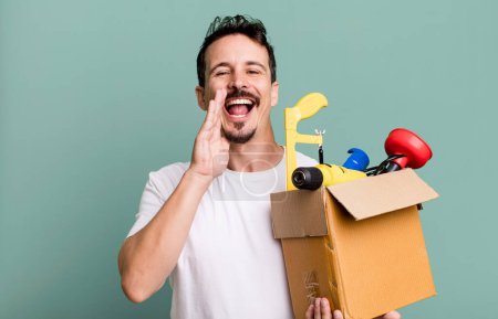 Foto de Adult man feeling happy,giving a big shout out with hands next to mouth. with a toolbox. handyman concept - Imagen libre de derechos