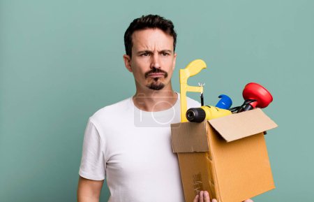 Téléchargez les photos : Adult man feeling sad, upset or angry and looking to the side. with a toolbox. handyman concept - en image libre de droit
