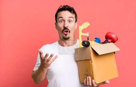 Photo for Adult man amazed, shocked and astonished with an unbelievable surprise. with a toolbox. handyman concept - Royalty Free Image