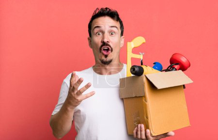 Téléchargez les photos : Adult man feeling extremely shocked and surprised. with a toolbox. handyman concept - en image libre de droit