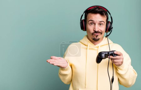 Téléchargez les photos : Adult man feeling puzzled and confused and doubting with headset and a control. gamer concept - en image libre de droit