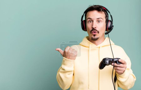 Téléchargez les photos : Adult man looking astonished in disbelief with headset and a control. gamer concept - en image libre de droit