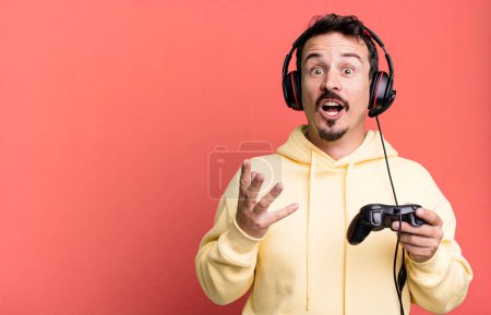 Photo for Adult man amazed, shocked and astonished with an unbelievable surprise with headset and a control. gamer concept - Royalty Free Image