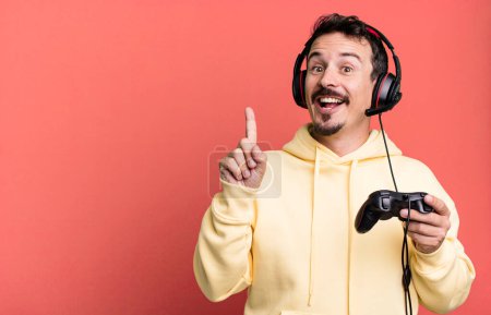 Téléchargez les photos : Adult man feeling like a happy and excited genius after realizing an idea with headset and a control. gamer concept - en image libre de droit
