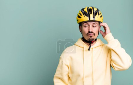 Photo for Adult man feeling puzzled and confused, scratching head. bike helmet and bicycle concept - Royalty Free Image