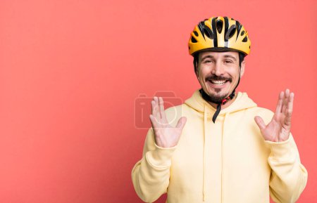 Foto de Adult man feeling happy and astonished at something unbelievable. bike helmet and bicycle concept - Imagen libre de derechos