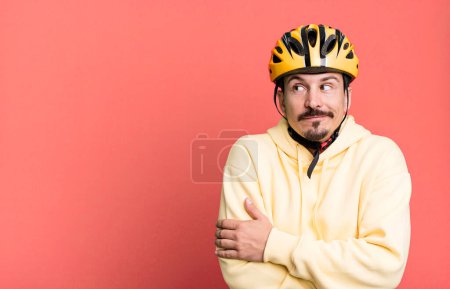 Photo for Adult man shrugging, feeling confused and uncertain. bike helmet and bicycle concept - Royalty Free Image
