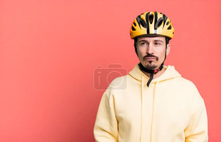 Foto de Adult man feeling sad, upset or angry and looking to the side. bike helmet and bicycle concept - Imagen libre de derechos