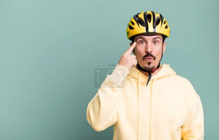 Photo for Adult man looking surprised, realizing a new thought, idea or concept. bike helmet and bicycle concept - Royalty Free Image