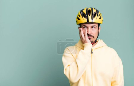 Téléchargez les photos : Adult man feeling bored, frustrated and sleepy after a tiresome. bike helmet and bicycle concept - en image libre de droit