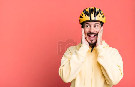 Téléchargez les photos : Adult man feeling happy, excited and surprised. bike helmet and bicycle concept - en image libre de droit