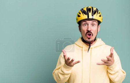 Téléchargez les photos : Adult man feeling extremely shocked and surprised. bike helmet and bicycle concept - en image libre de droit
