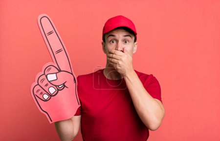 Téléchargez les photos : Homme adulte couvrant la bouche avec les mains avec un choc. numéro un concept de ventilateur - en image libre de droit